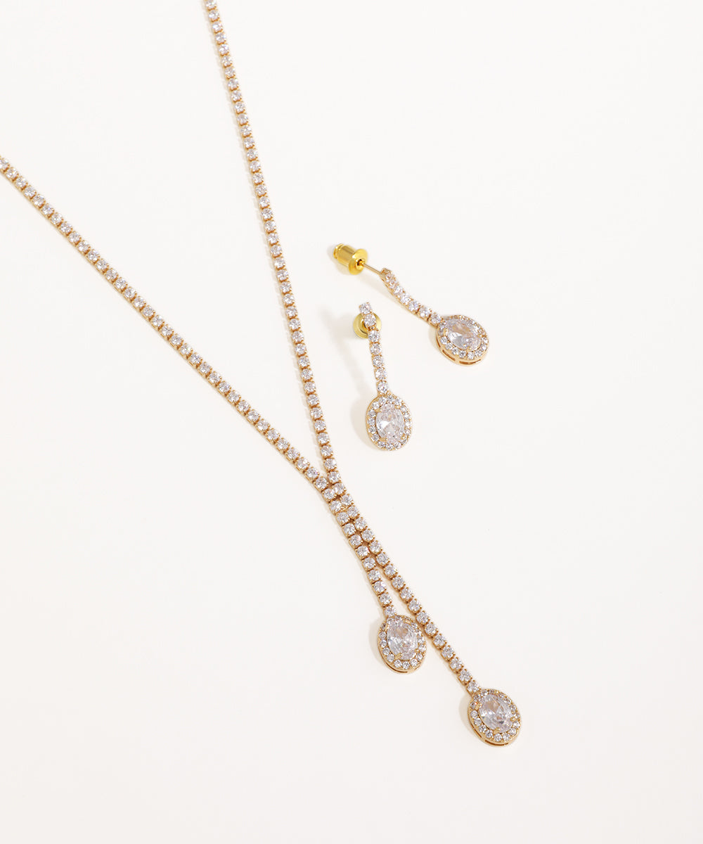 Gold necklace and earrings with clear stones on a white background