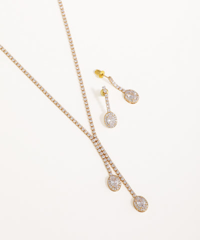 Gold necklace and earrings with clear stones on a white background