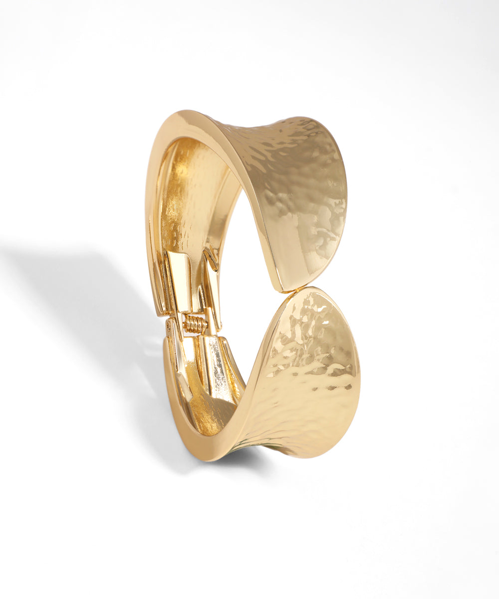 Gold-tone bangle bracelet with a wavy, hammered texture and sculptural design