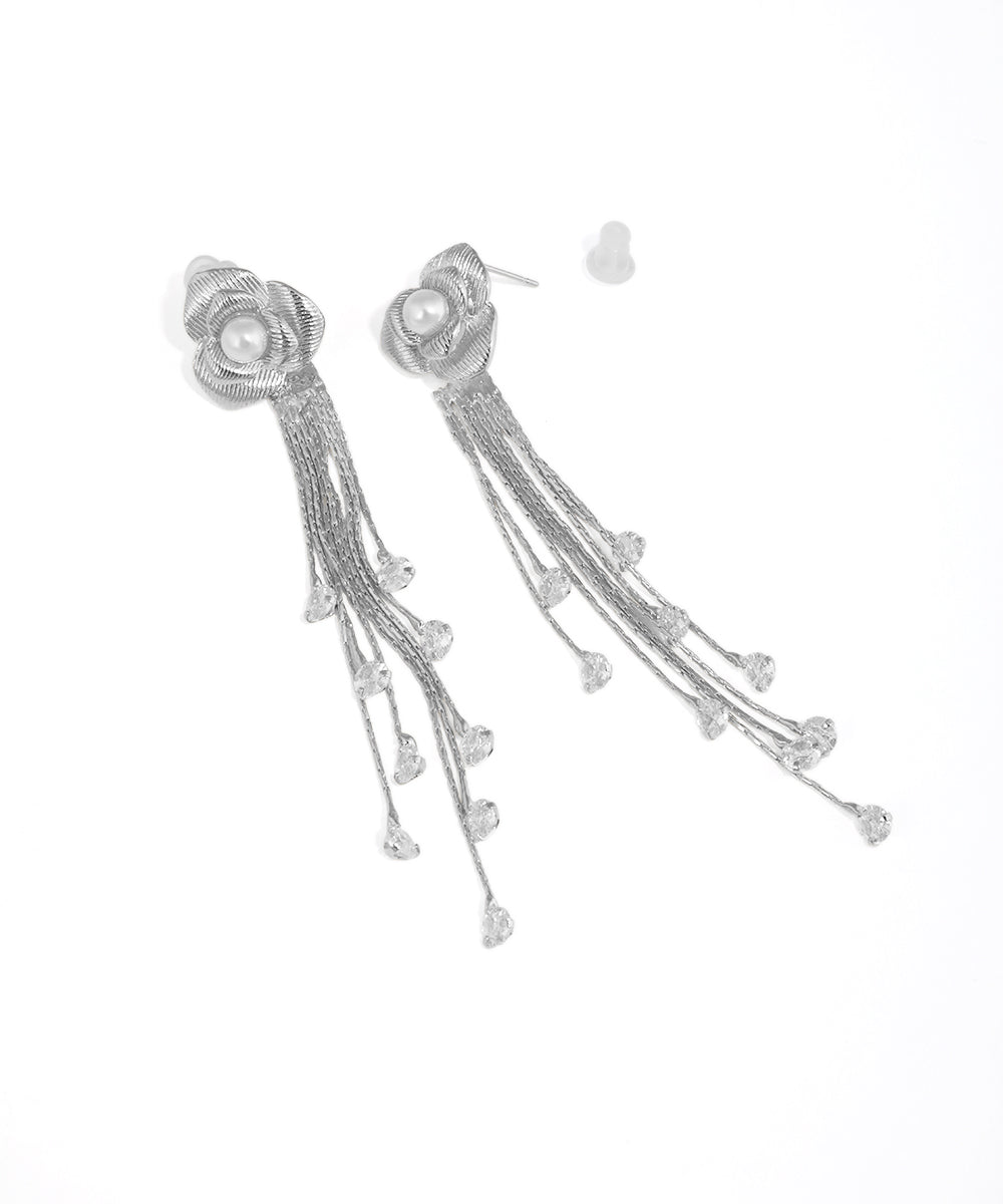 Silver earrings with floral design and tassels on a white background