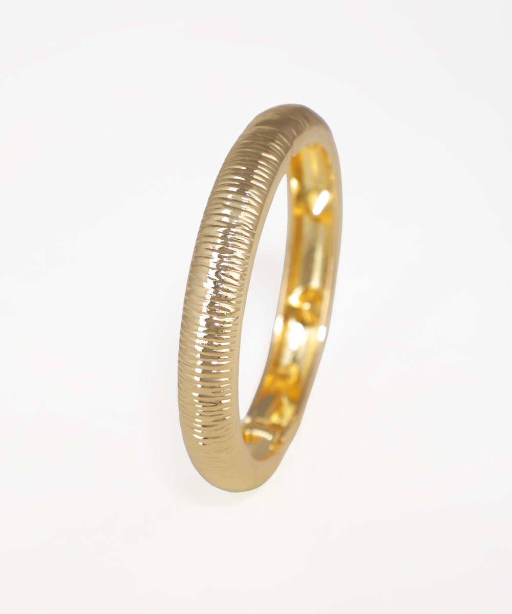 Gold ring with textured design on a white background