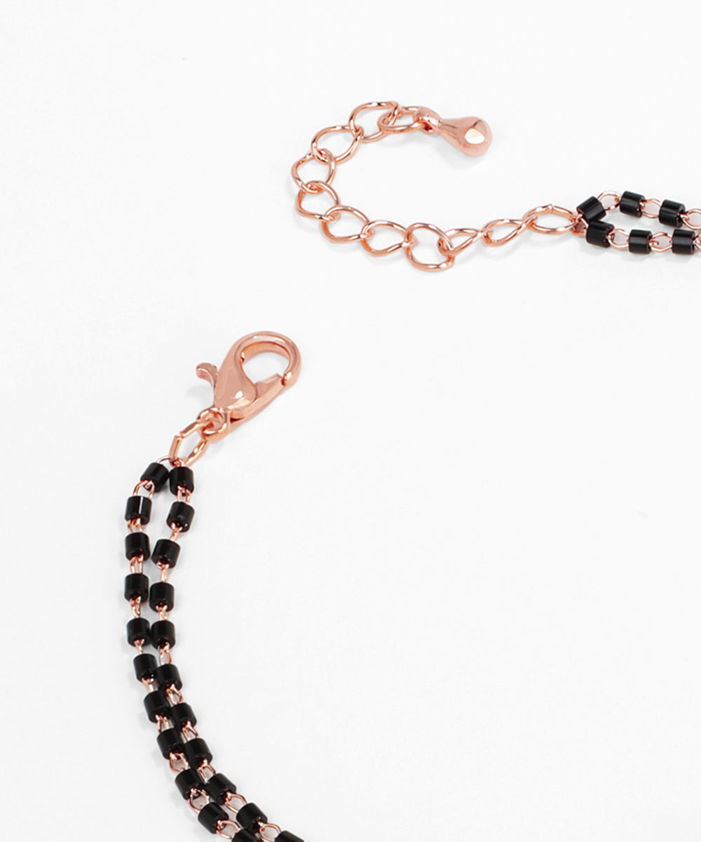 Rose gold and black beaded bracelet on a white background