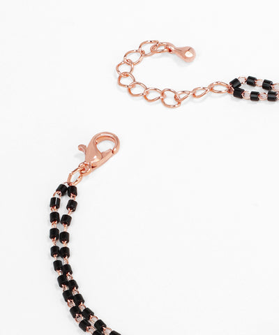 Rose gold and black beaded bracelet on a white background