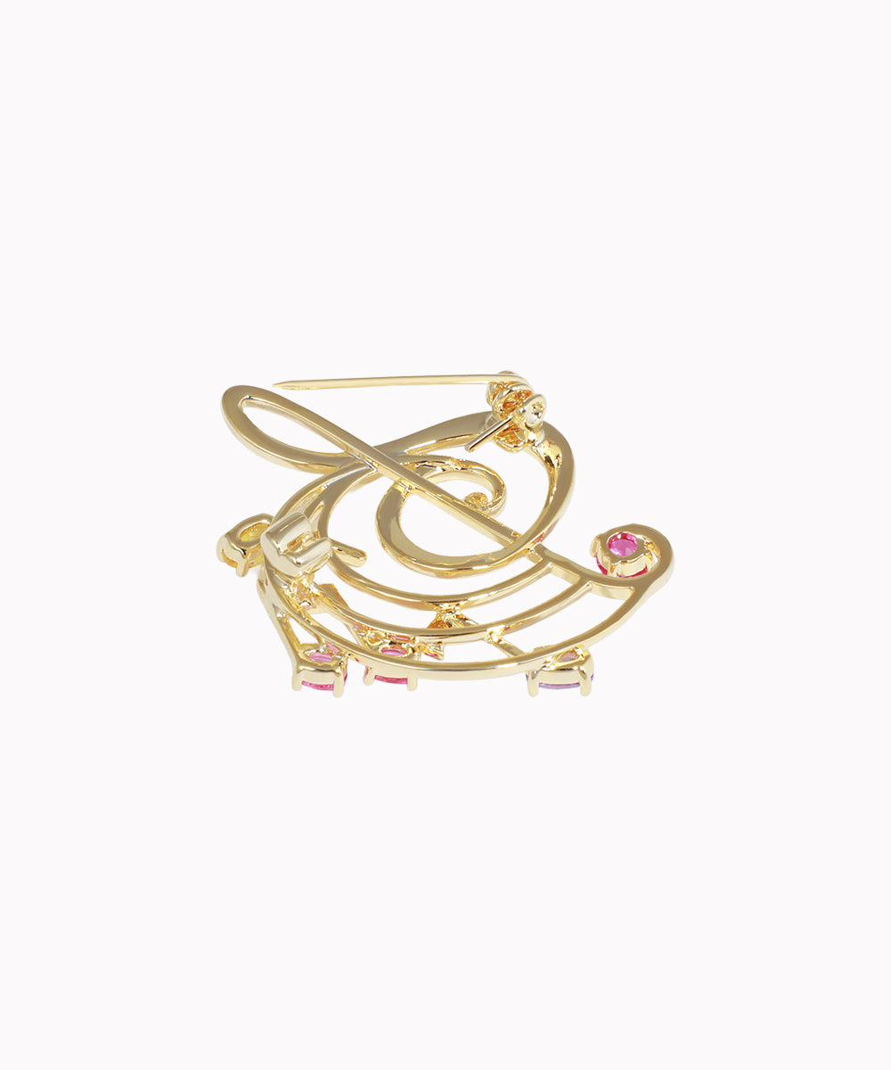 Gold brooch with musical note design on a white background