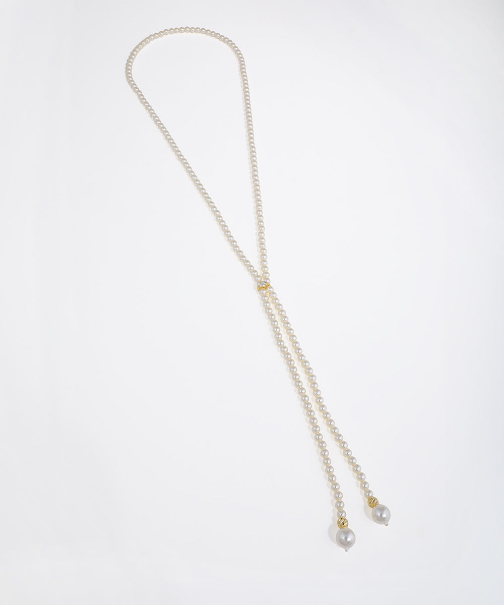 Gold-tone lariat necklace with small faux pearls, a clear CZ accent, and larger faux pearl drops.