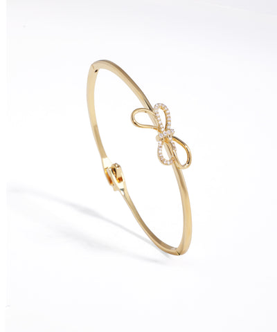 Gold-tone hinged bracelet with a sparkling CZ-studded bow motif