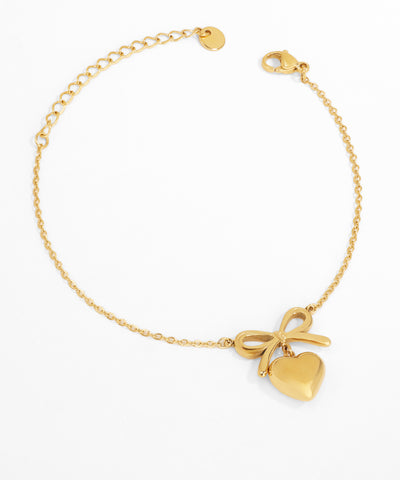 Gold bracelet with heart and bow charm on a white background