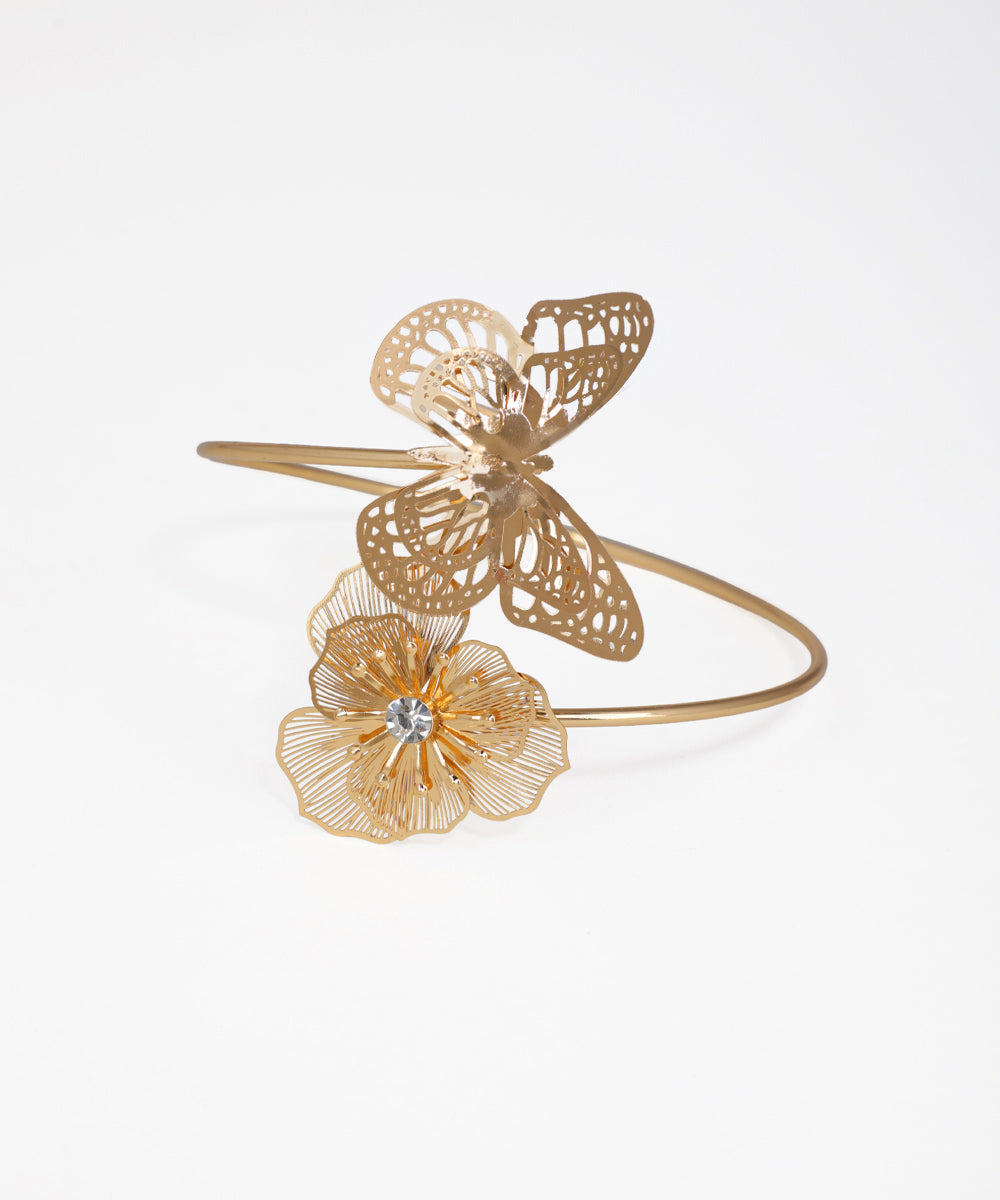 Gold bracelet with butterfly and flower designs on a white background
