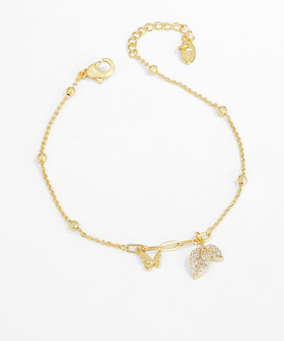 Gold bracelet with leaf charms on a white background