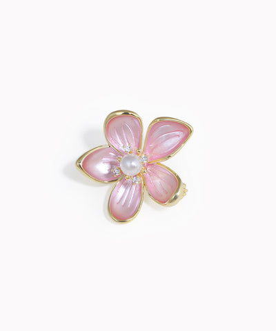 Gold-tone floral brooch with pink petals, a central faux pearl, and clear accent stones.