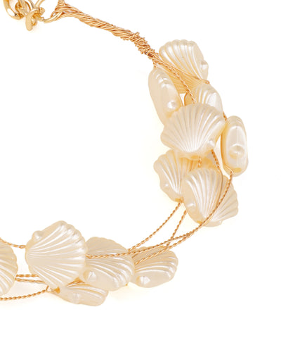 Bracelet with shell-like beads on a gold chain against a white background