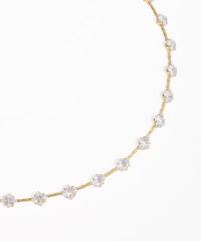 Gold necklace with clear stones on a white background