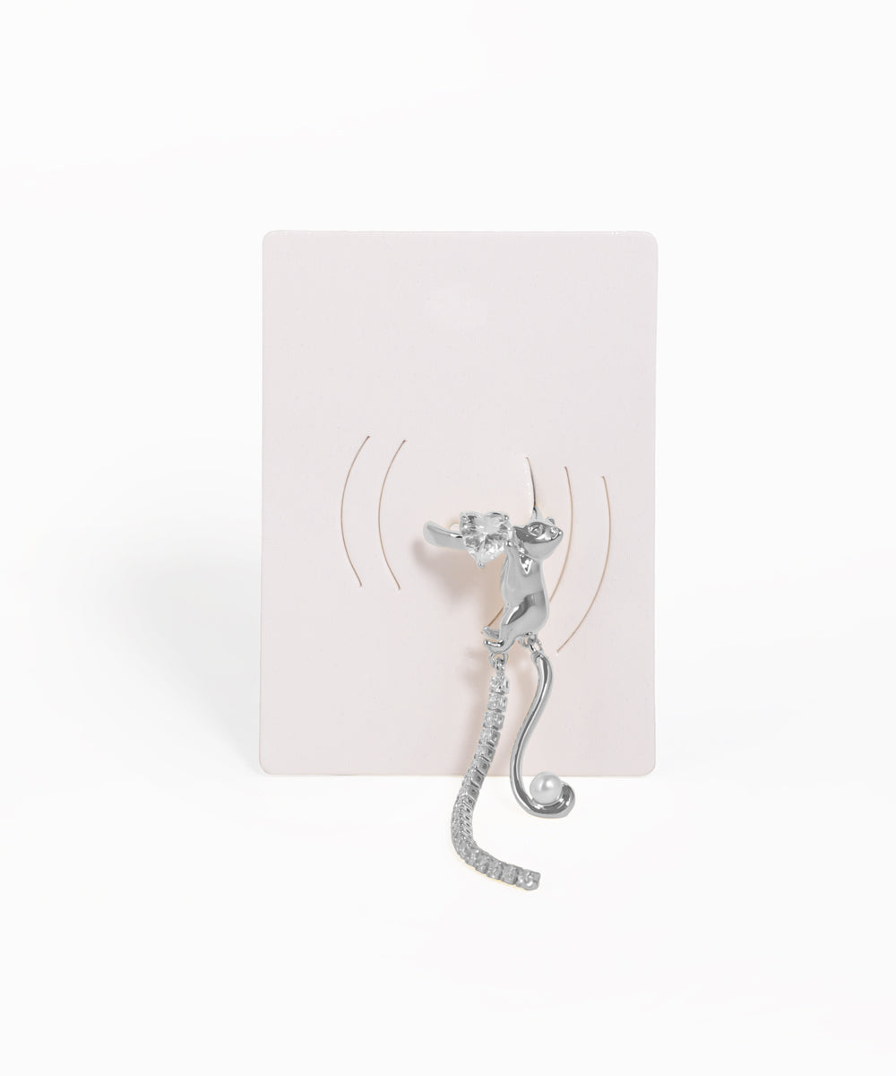 Silver cat-shaped earring on a white card with a white background