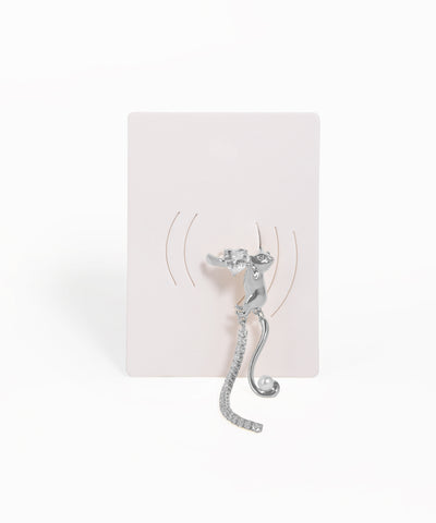 Silver cat-shaped earring on a white card with a white background