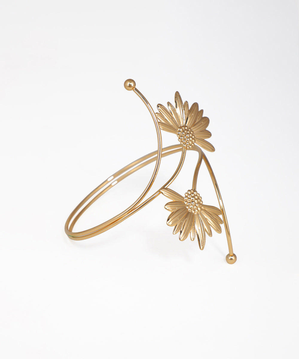 Gold bracelet with floral designs on a white background