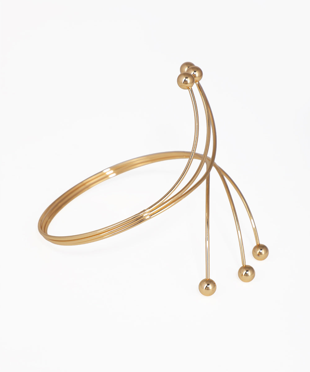 Gold bracelet with spherical beads on a white background