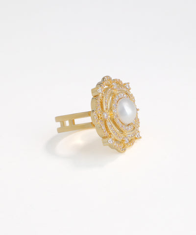 Gold hair clip with a central pearl on a white background