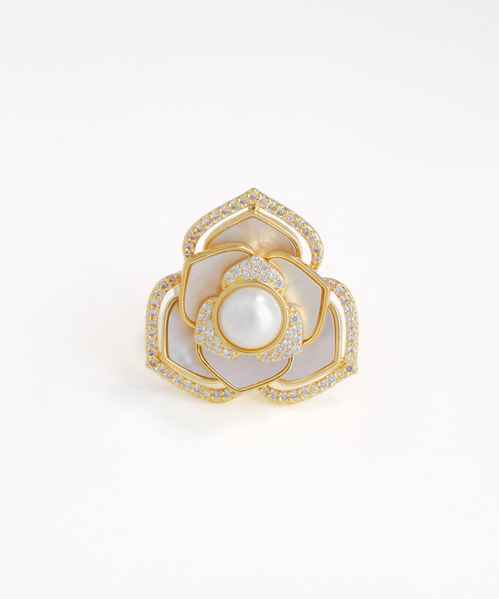 Gold ring with a central pearl and diamond-studded design on a white background