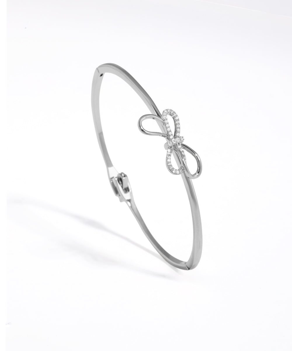 Silver bracelet with bow design on a white background
