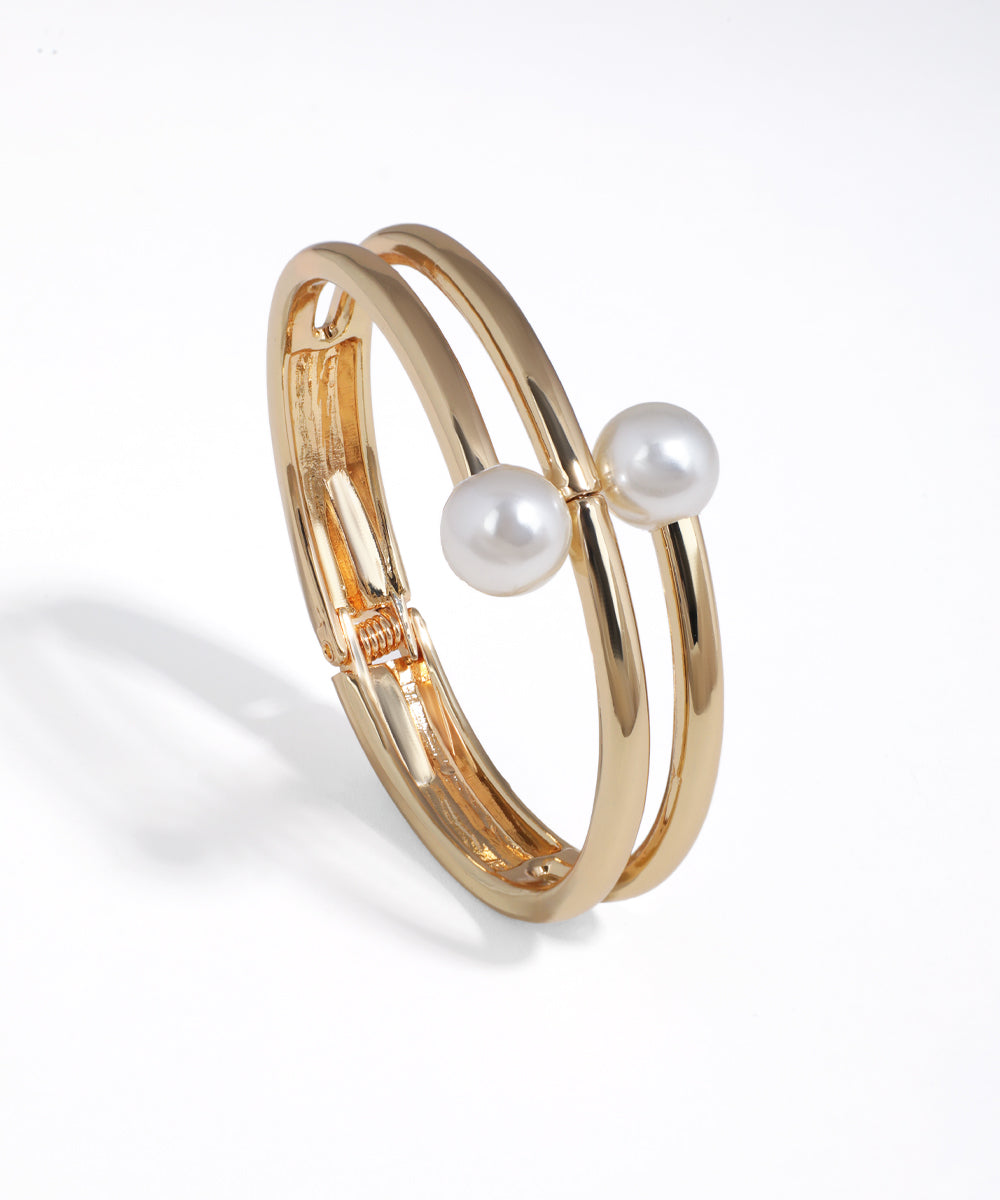 Gold-tone double band bracelet with two white faux pearls and a hinge clasp
