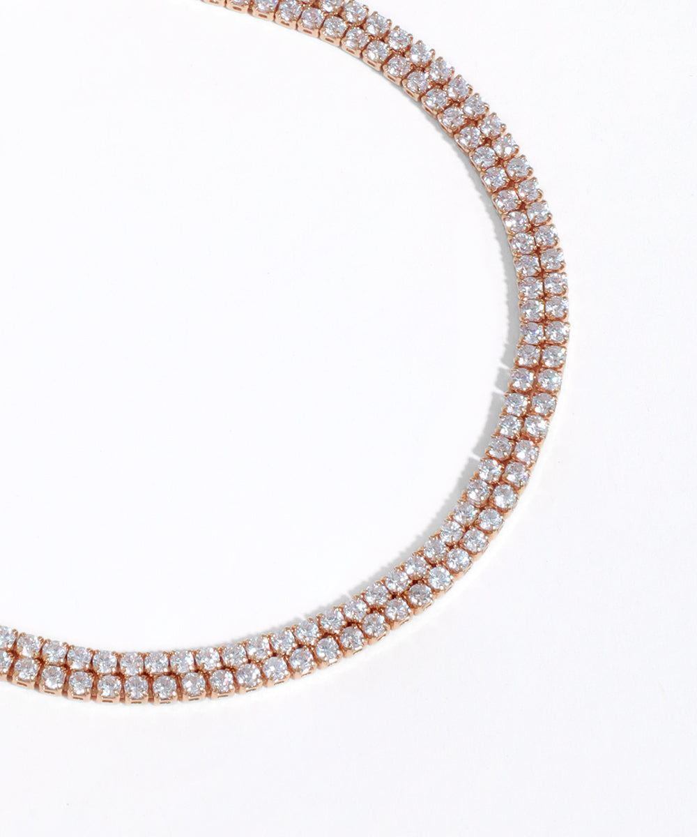 Rose gold necklace with clear gemstones on a white background