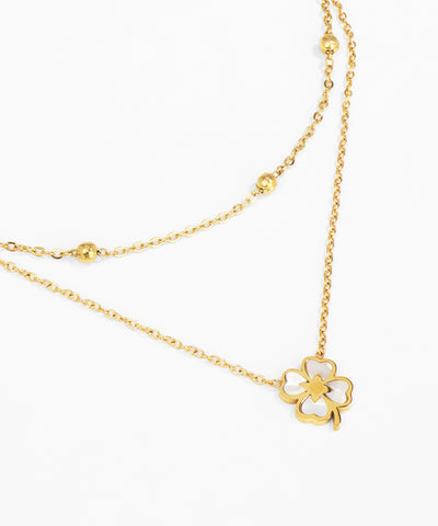 Gold necklace with a white flower pendant on a white background