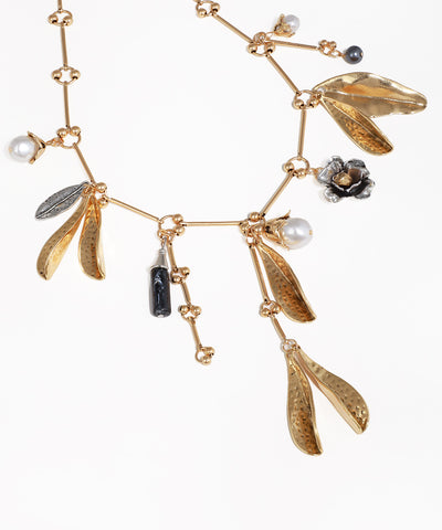 Gold necklace with leaf and flower pendants on a white background