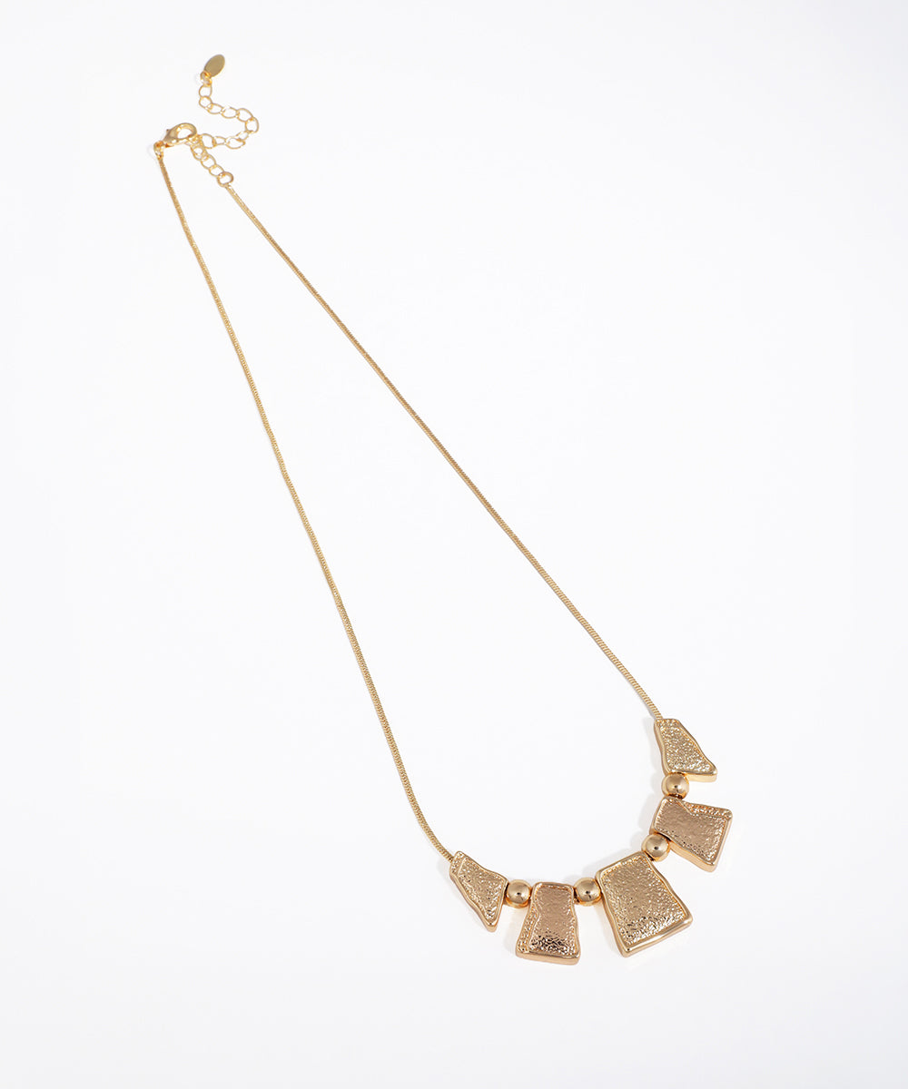 Gold-tone necklace with hammered geometric segments and round beads on a snake chain