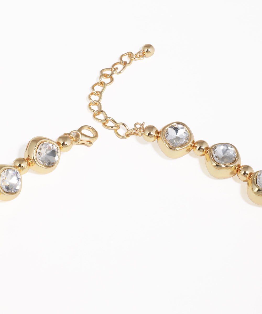 Gold bracelet with clear gemstones on a white background