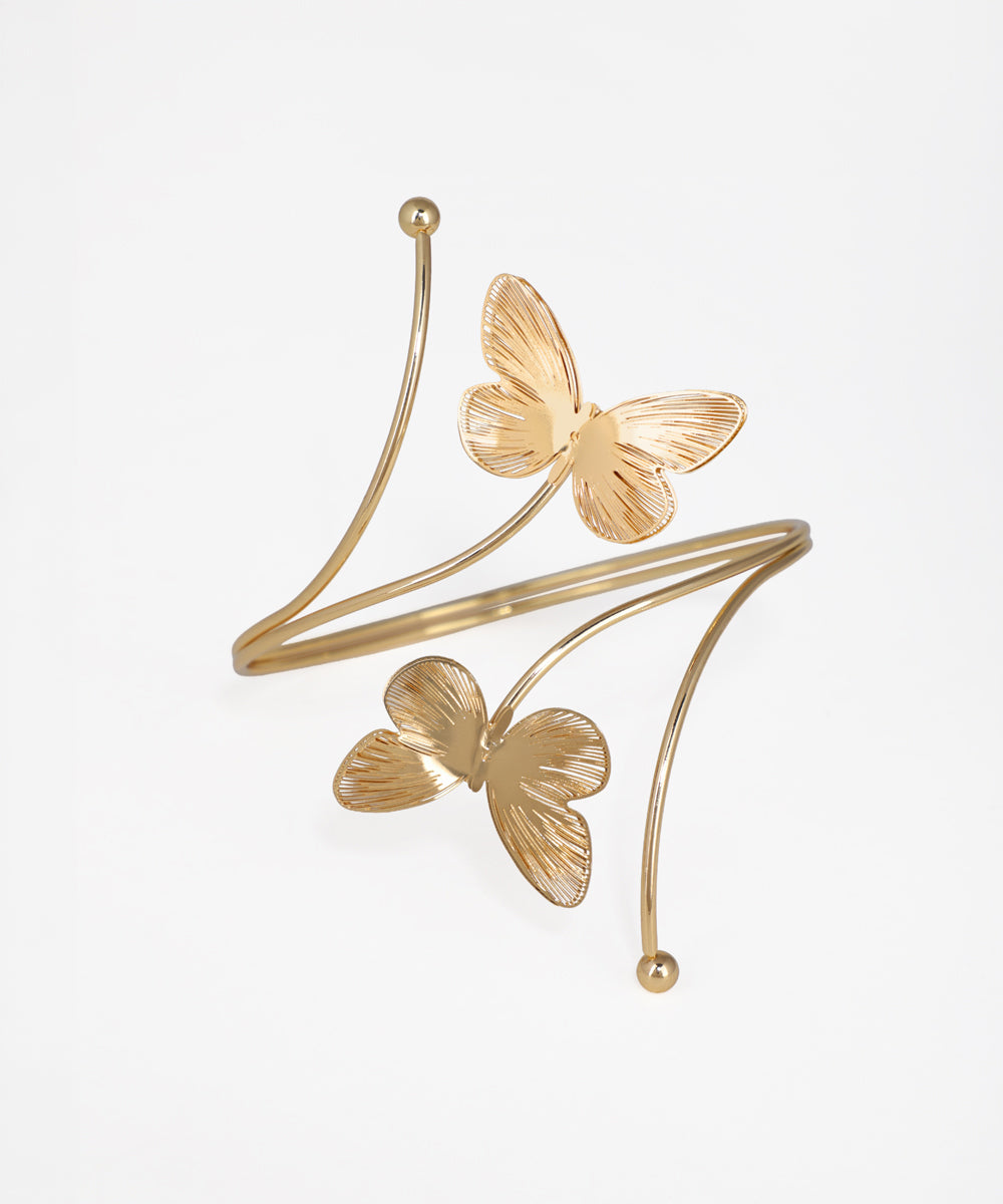 Gold butterfly-shaped cuff bracelet on a light gray background