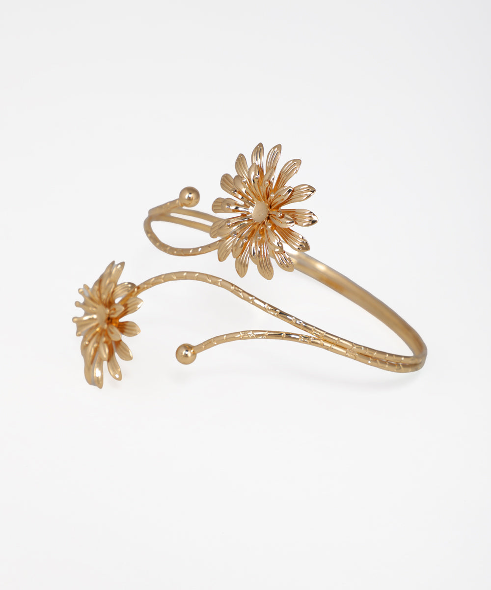 Gold bracelet with floral designs on a white background
