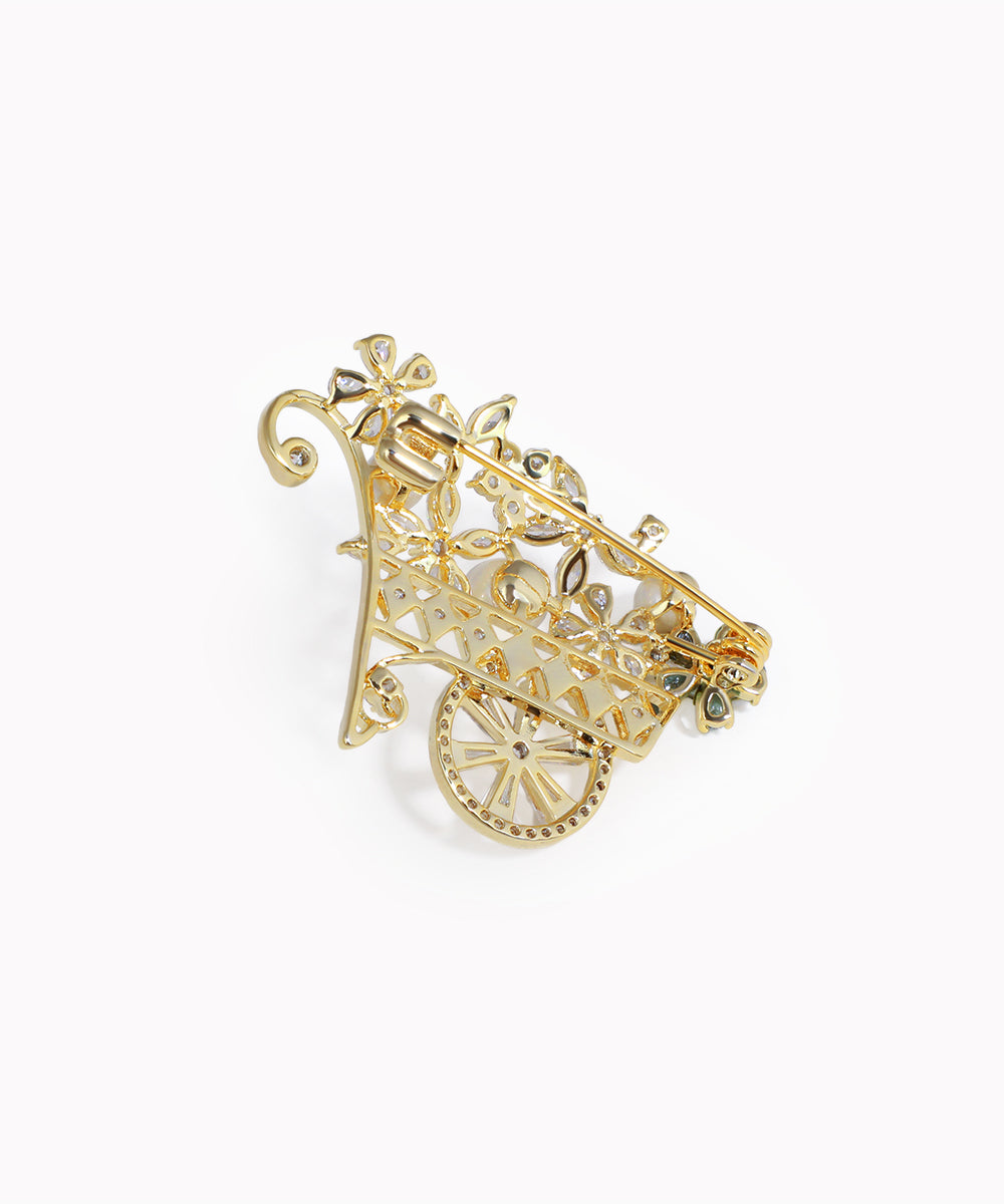 Gold-tone brooch with floral garden cart design and clear cubic zirconia stones.