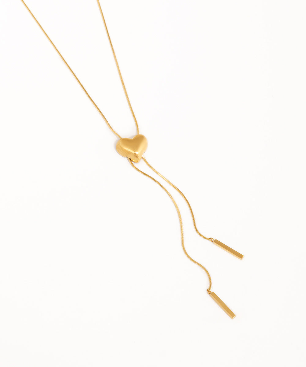 Gold necklace with a heart-shaped pendant on a white background