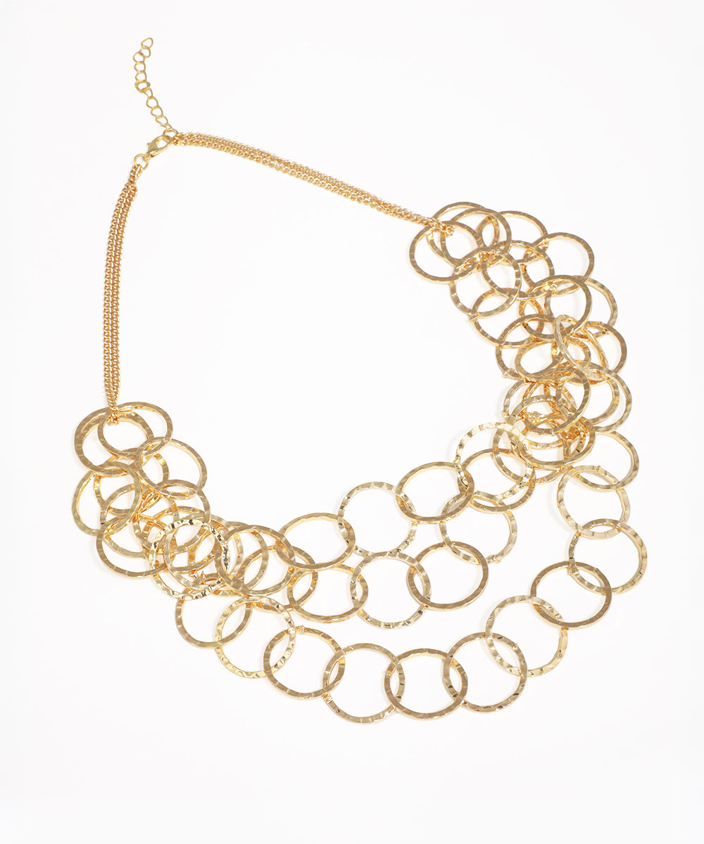 Gold-tone necklace with multiple layers of textured, hammered open rings creating a statement design