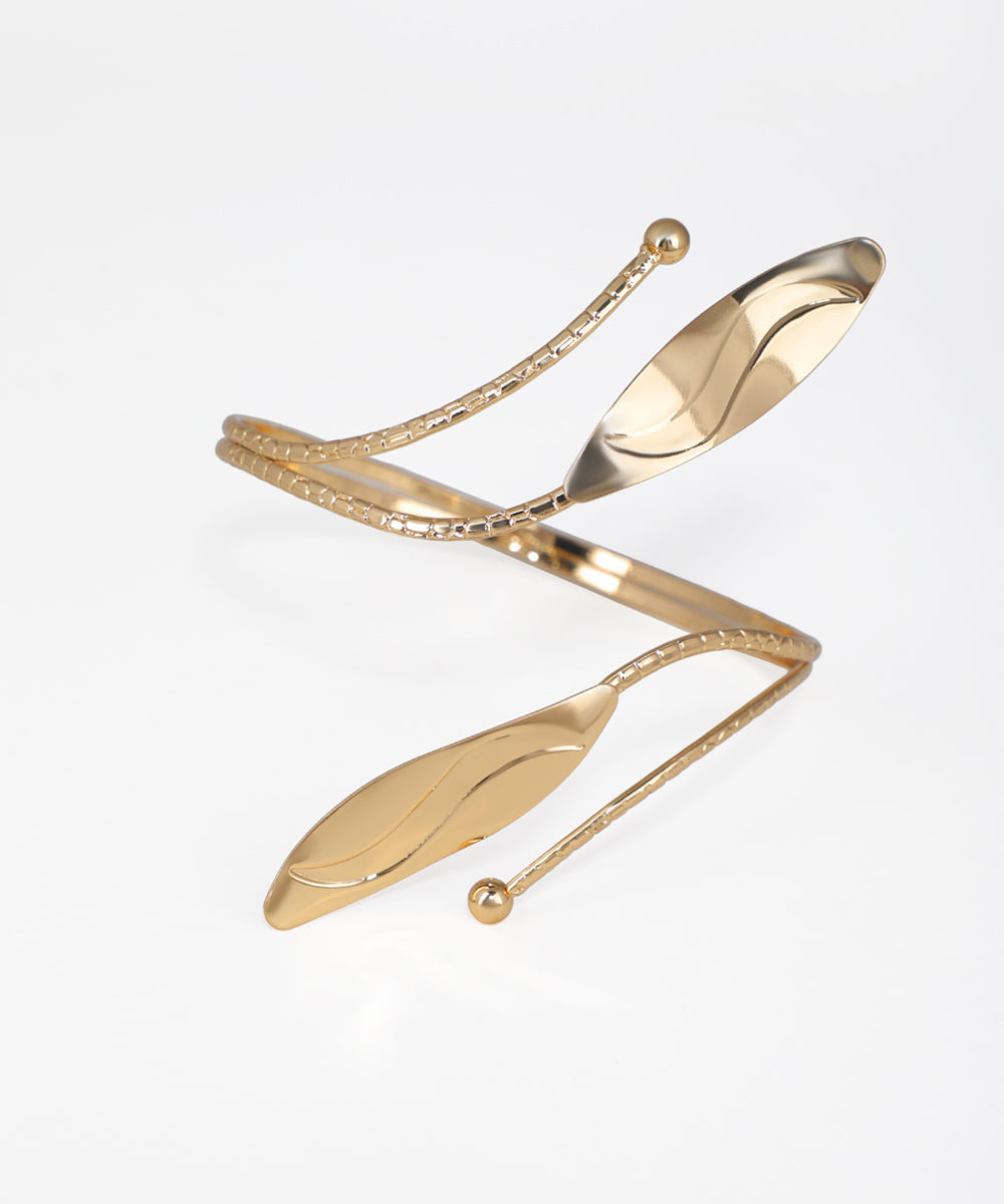 Gold bracelet with leaf-like design on a white background