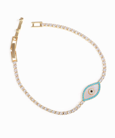 Gold bracelet with a blue and white evil eye charm on a white background