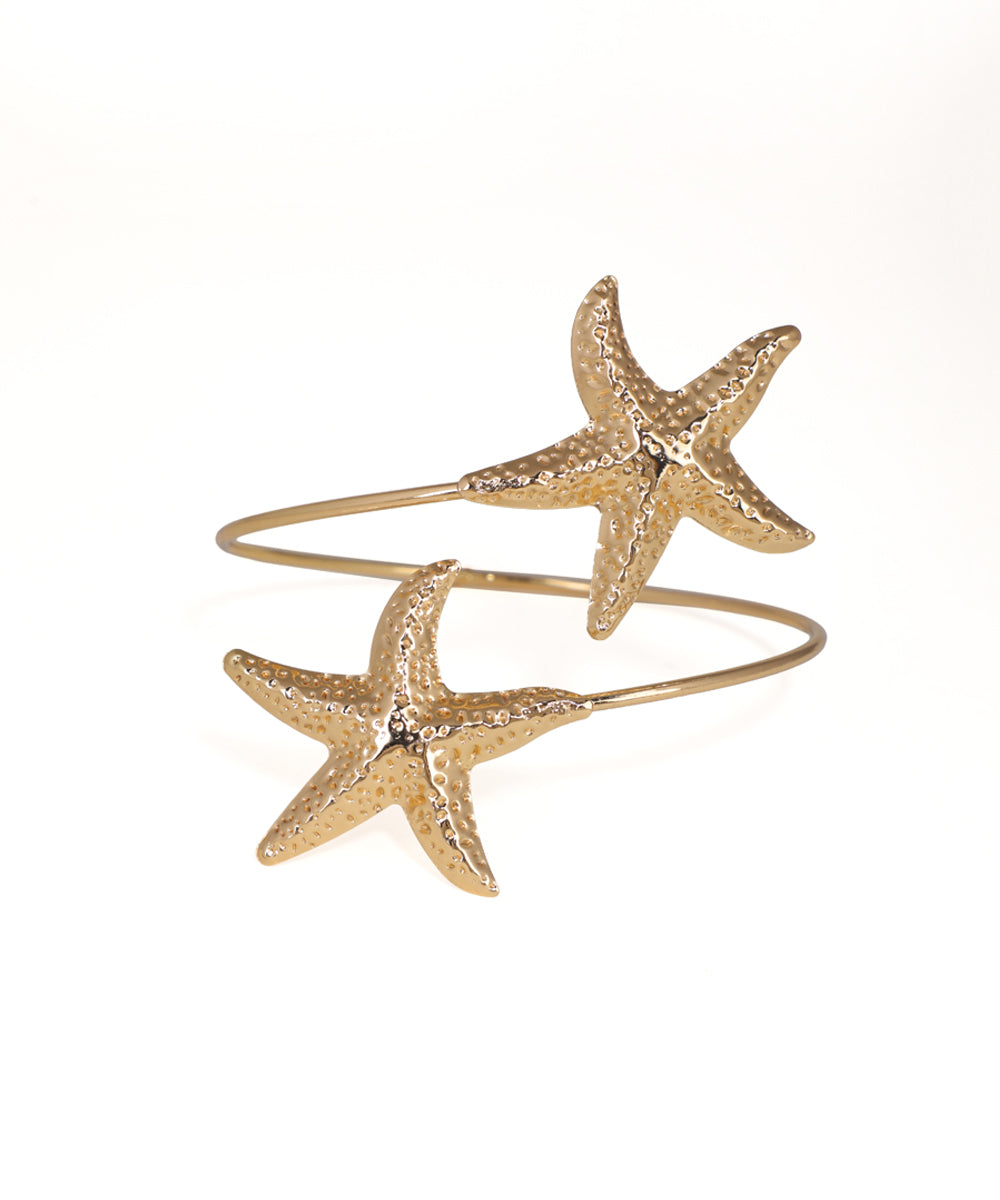 Gold starfish-shaped cuff bracelet on a white background