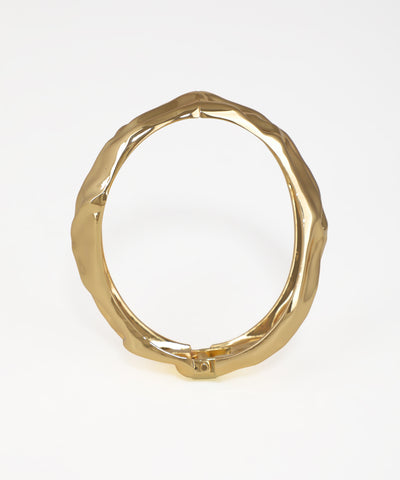 Gold ring with a textured design on a white background
