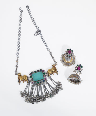 Oxidized silver-tone necklace with gold-tone Nandi bull motifs, blue-green stone, and ghungroo drops.