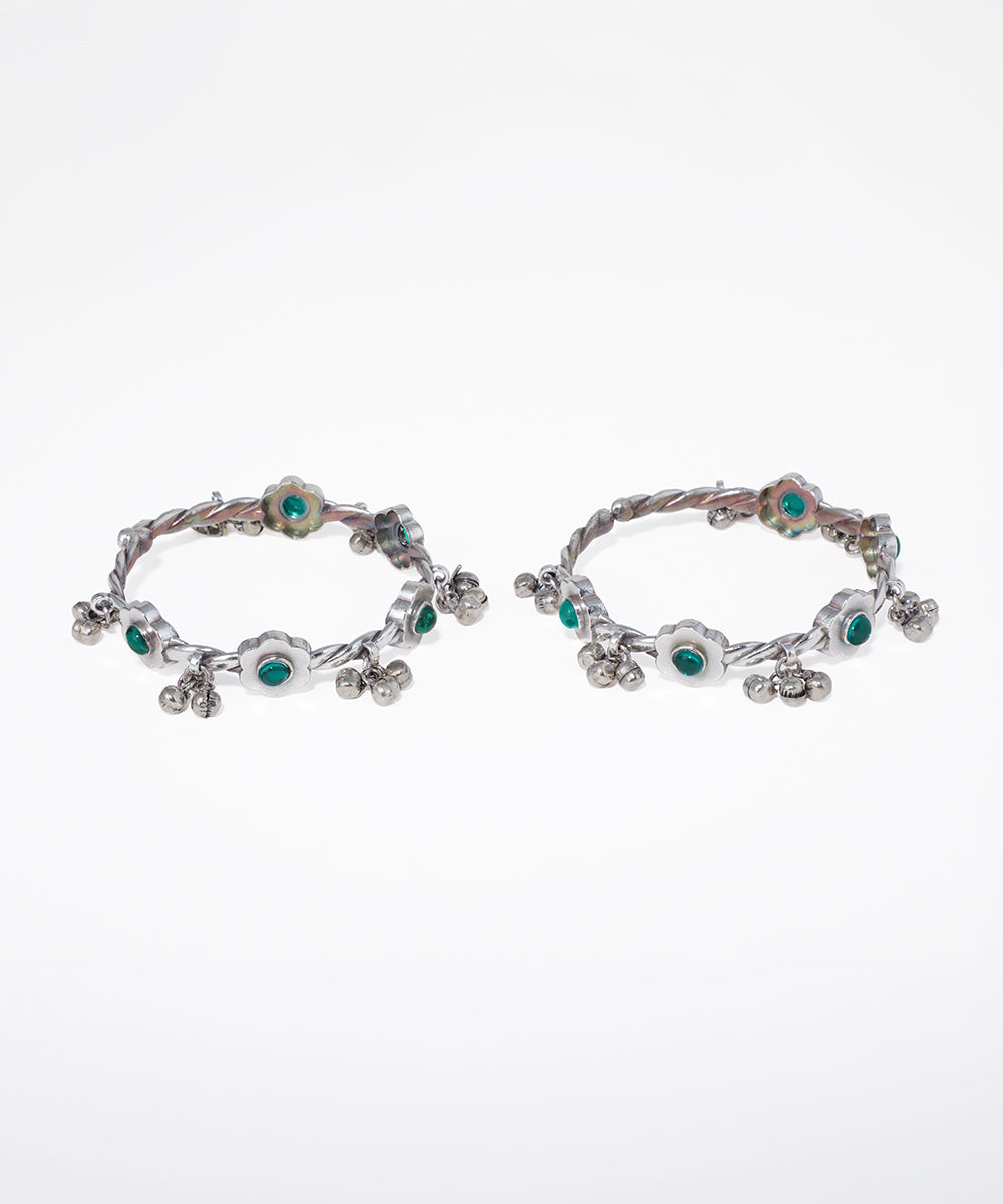 Pair of silver hoop earrings with green gemstones on a white background