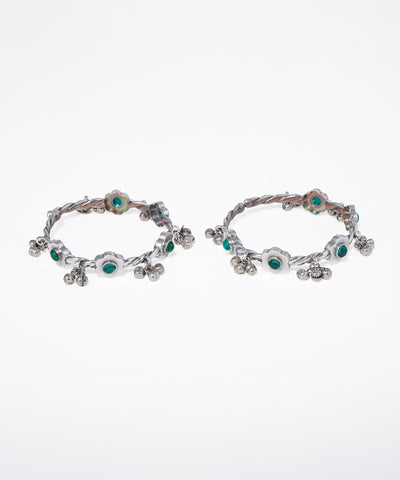 Pair of silver hoop earrings with green gemstones on a white background