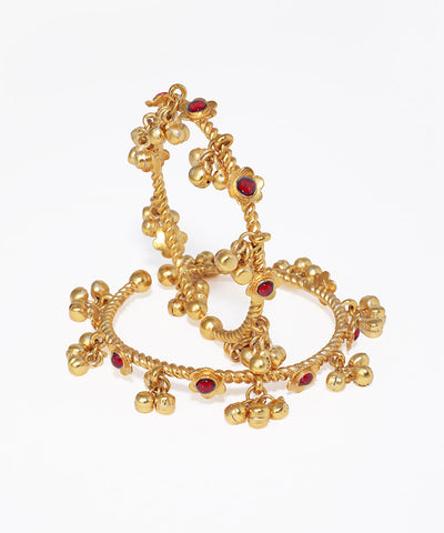 Gold bangles with red stones on a white background
