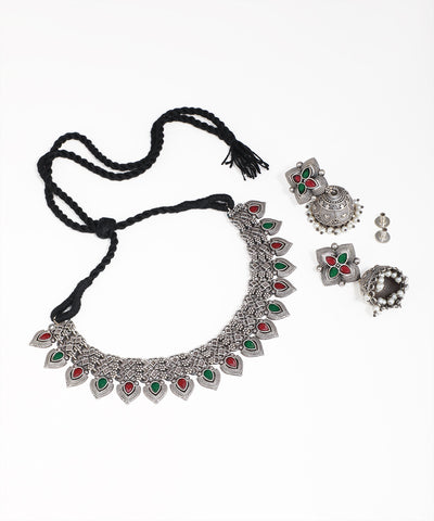 Silver necklace with green and red stones and matching earrings on a white background
