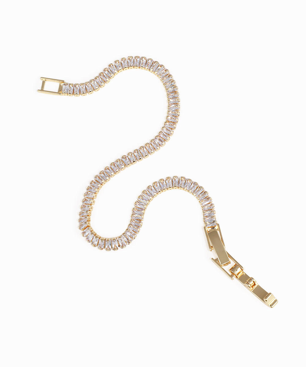 Gold bracelet with clear gemstones on a white background
