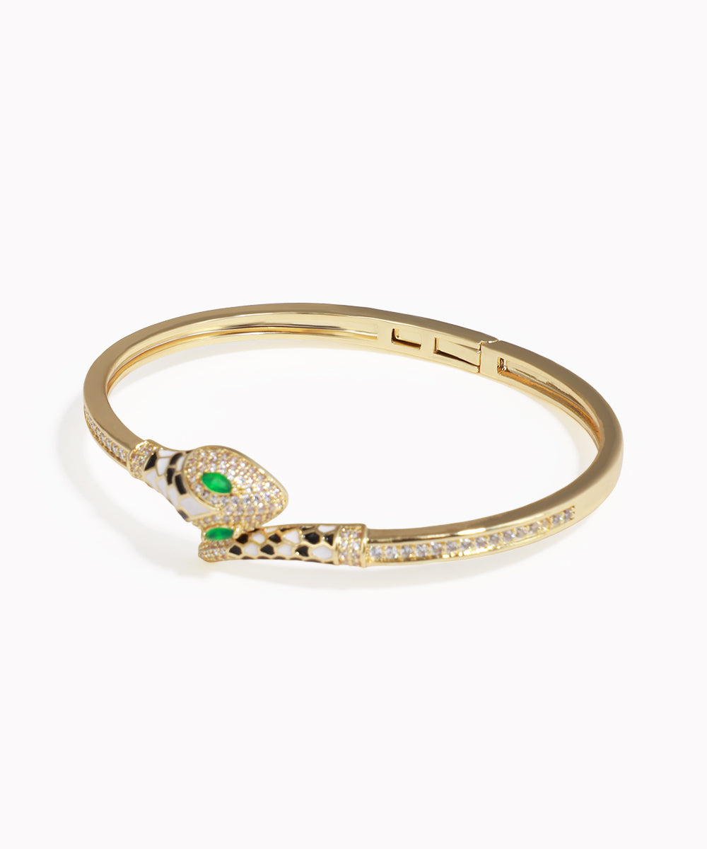 Gold bracelet with snake design and green gemstones on a white background