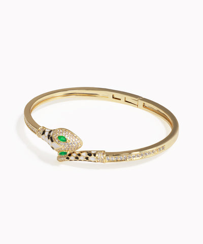 Gold bracelet with snake design and green gemstones on a white background