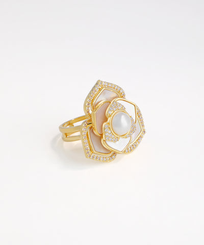 Gold ring with white stone on a light gray background
