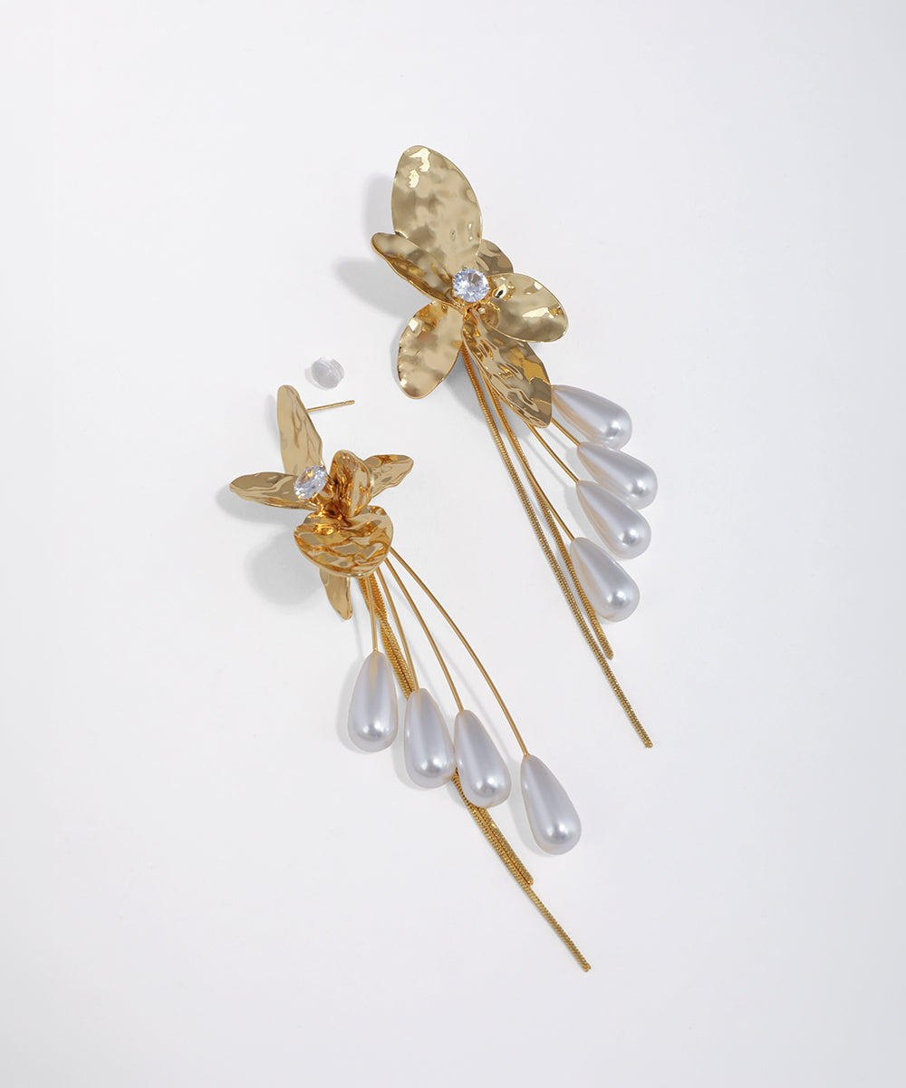 Gold-tone floral drop earrings with hammered texture, clear CZ, and multiple strands of faux pearl drops.