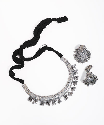 Silver necklace and earrings set with black ribbon on a white background