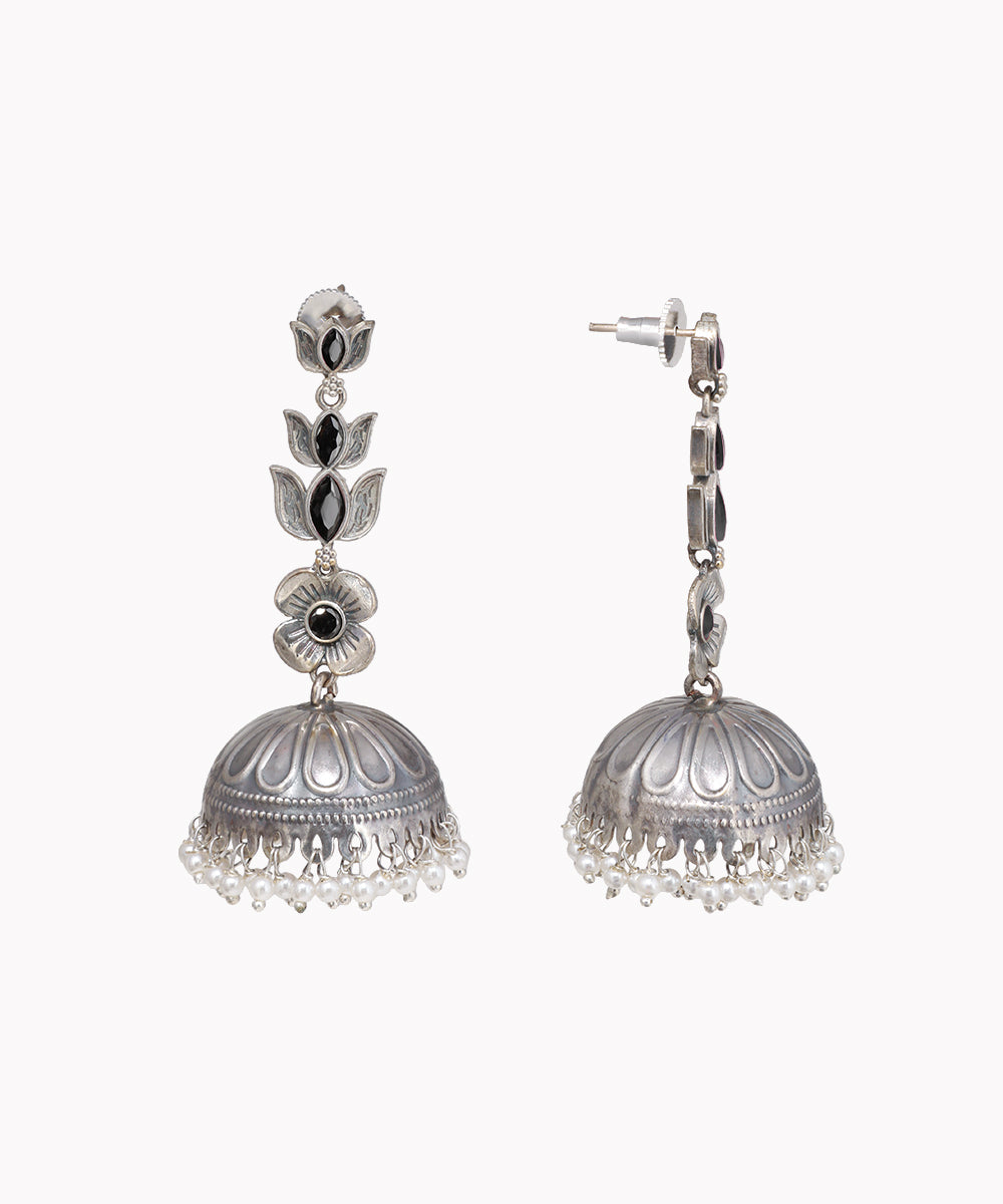 Pair of silver jhumka earrings with black stones on a white background